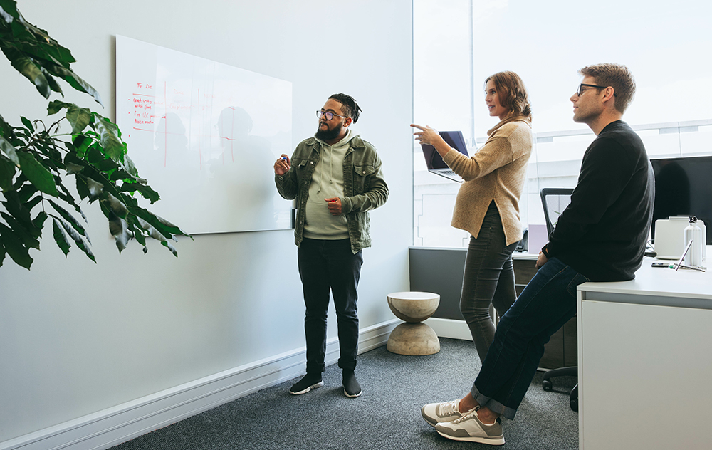 People standing a whiteboard discussing a project