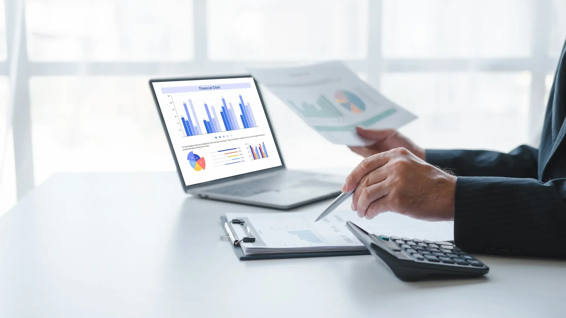 person sitting at a desk with a laptop with reports